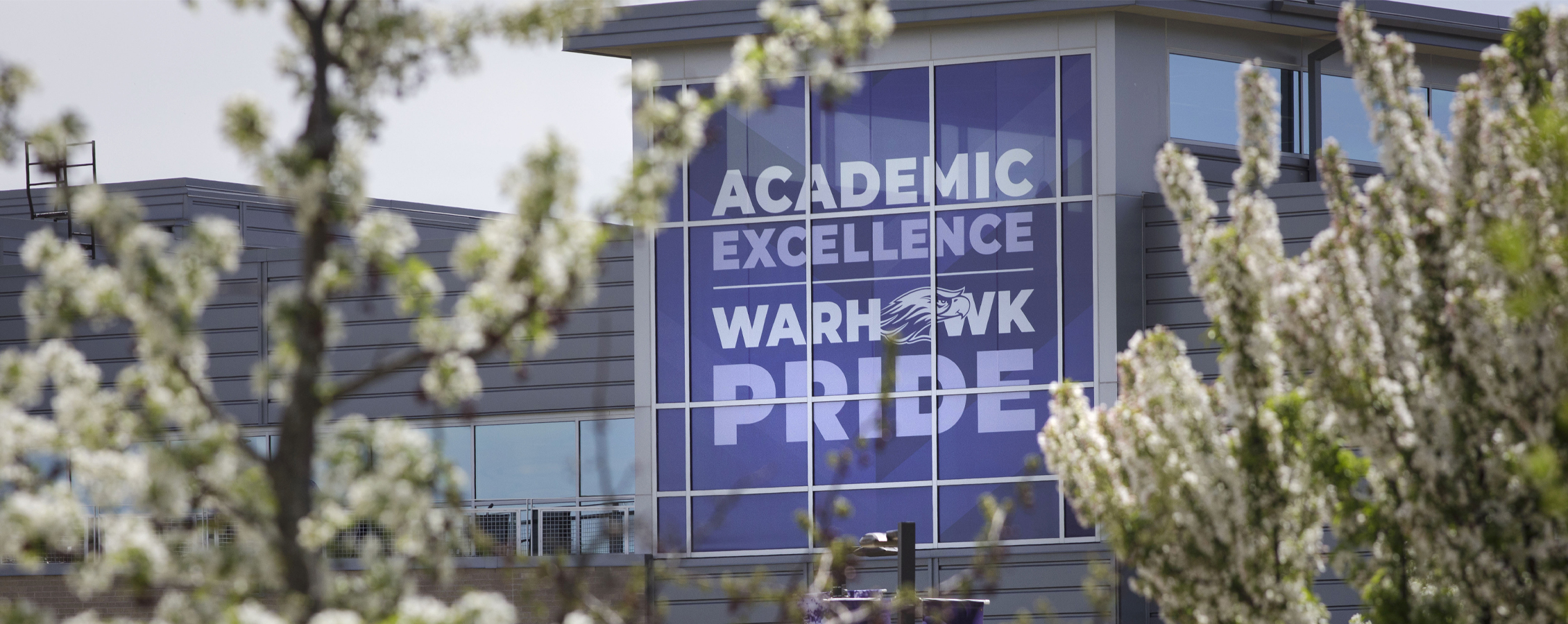 An exterior photo of the University Center with a large purple banner in the window that says academic excellence.