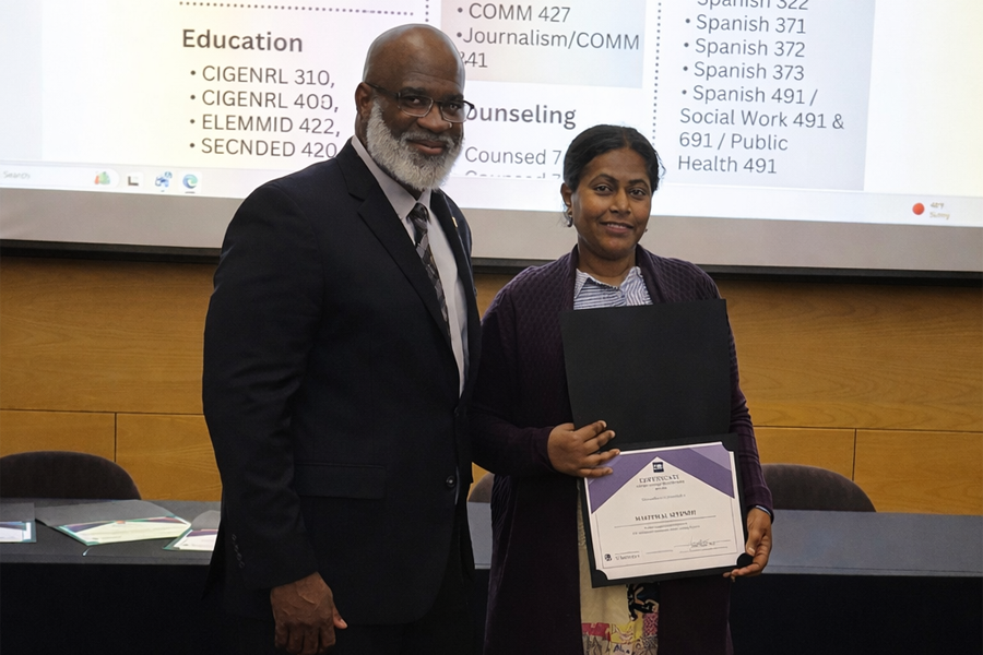 Two people stand together holding an award.