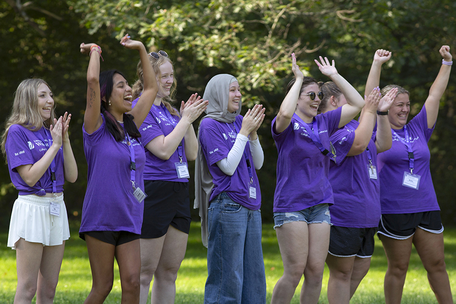 A group of students wear purple shirts and raise their arms as they cheer each other on during a leadership exercise.