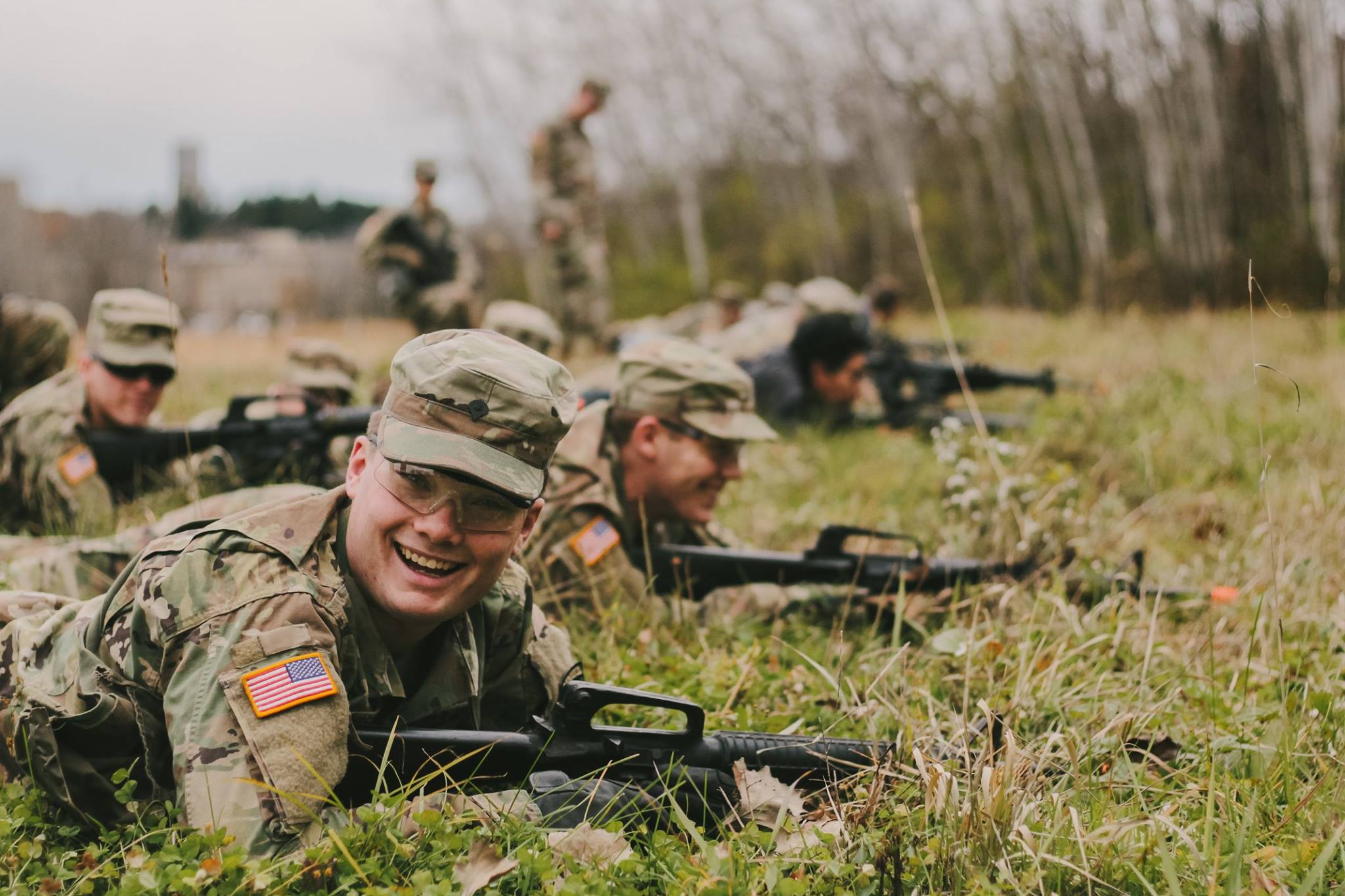 students in uniform smiling while crawling through a field