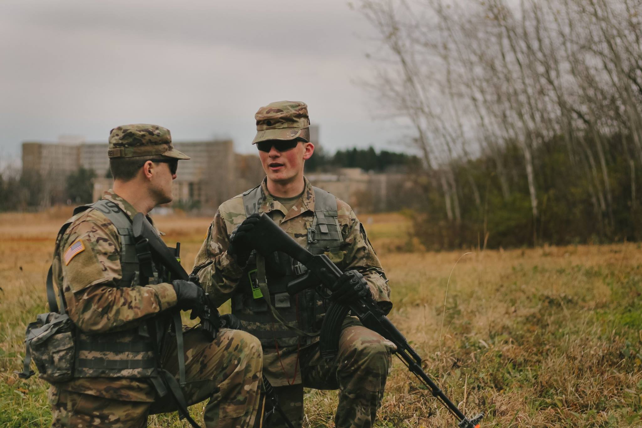 student in uniform kneeling in a field talking strategy