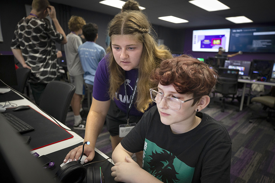 A person helps a young student on the computer.