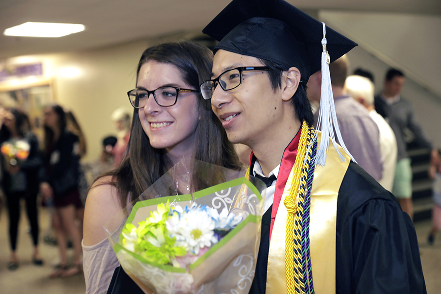 Two people stand together at graduation and pose for a photo.