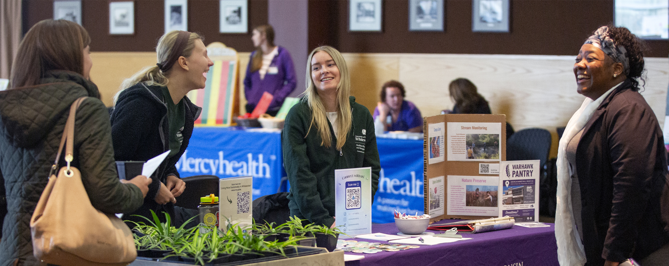 People smile and laugh together as they gather around a table during a benefits fair.