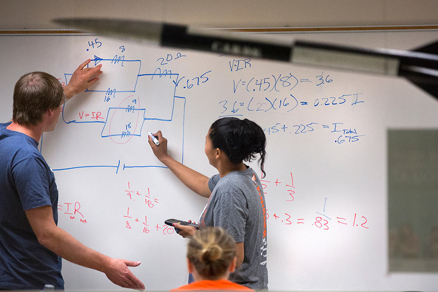 Physics students taking a test on a whiteboard