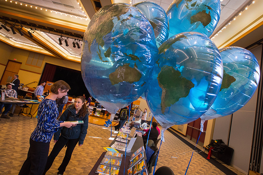 Two people talk in the Hamilton Room of the University Center with blue balloons in the foreground.