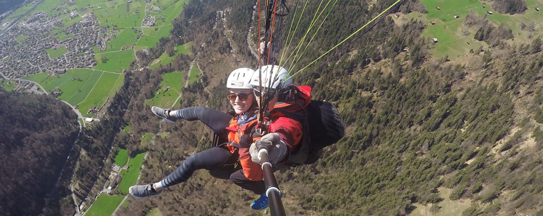 A person skydives while taking a selfie with a selfie stick.