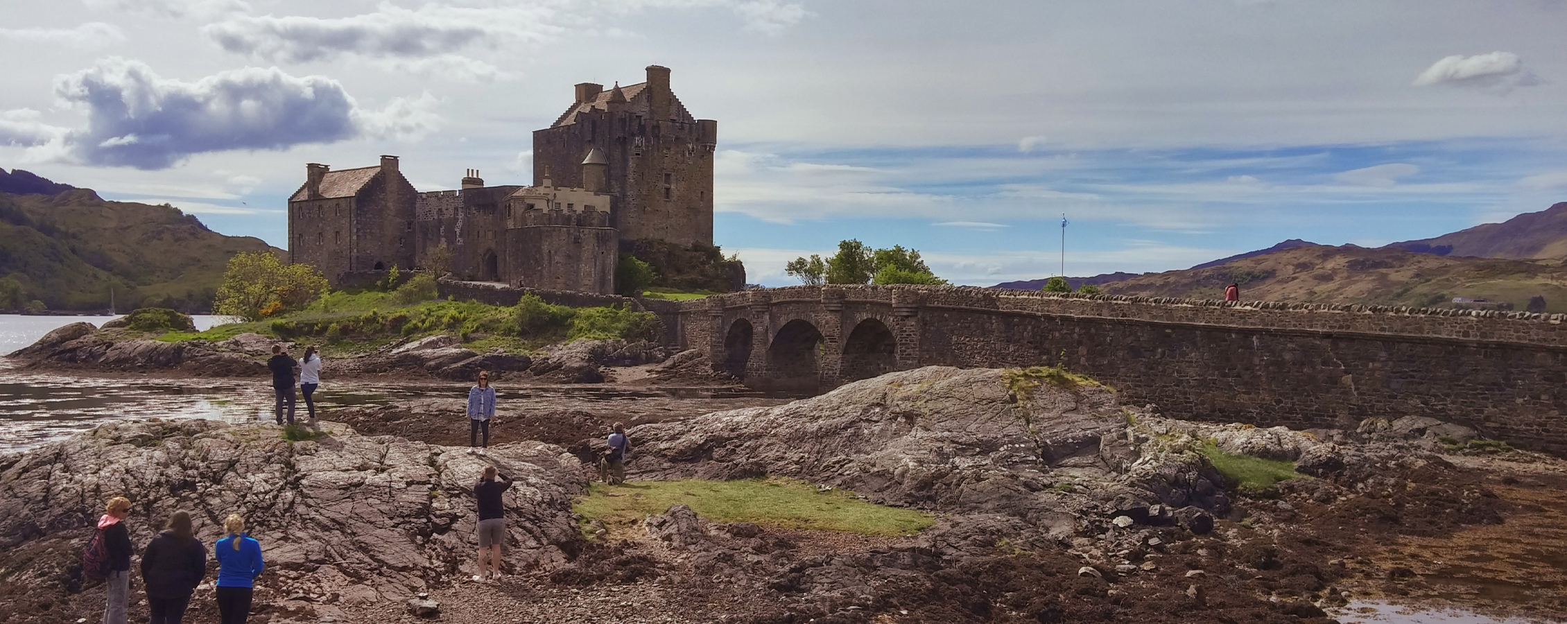 People walk at the foot of a large castle.