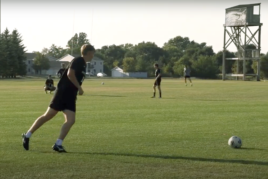 A soccer player hangs back to kick the ball onto the field.