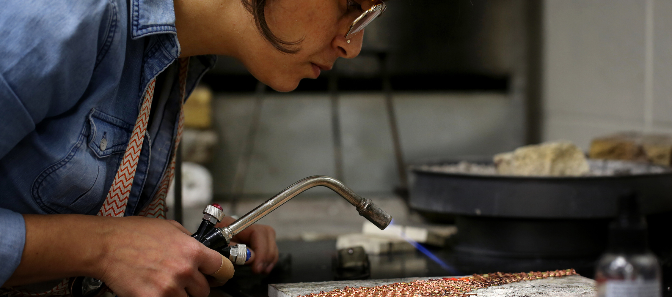 An international student from Israel uses a small torch to solder jewelry.