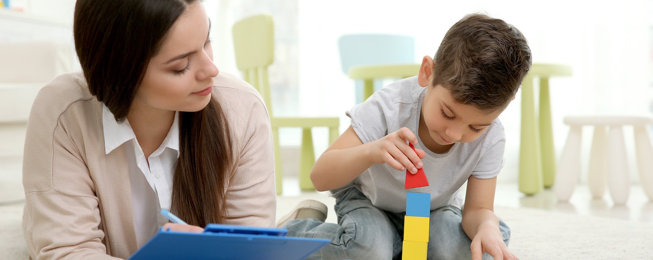 Teacher watching child play with blocks.