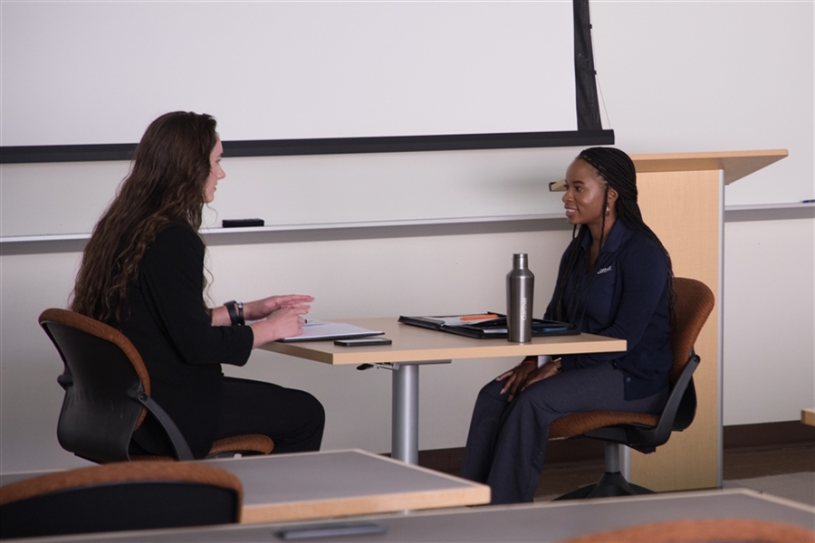 Two people sit together at a table and have a conversation.