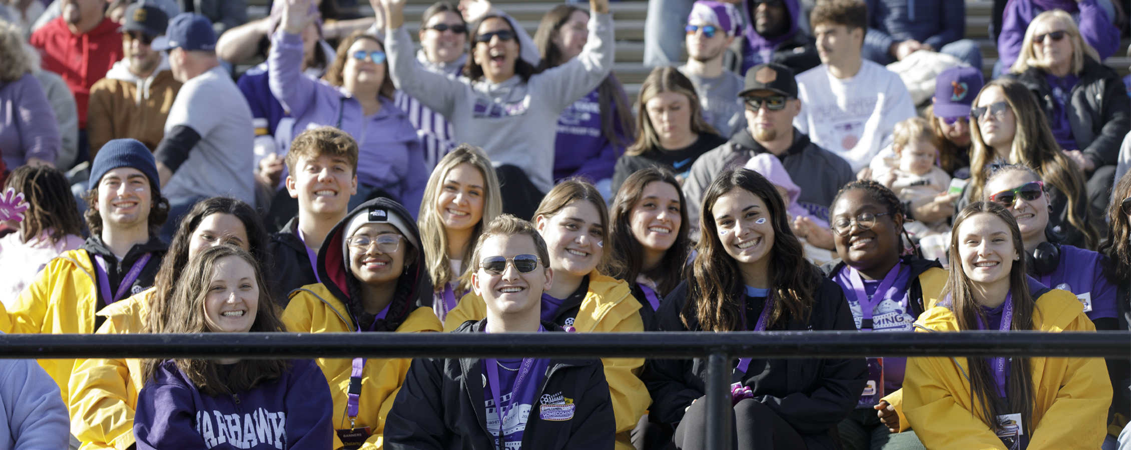 A crowd of people watch the football game in the stands.