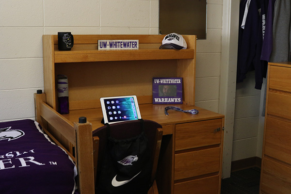 A desk with an iPad, a water bottle and a picture on top of it.