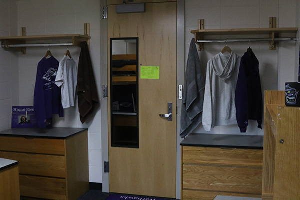 Two shelfs on the left and right sides of the door. Each shelf has a bar with clothes hanging on it, and there a dressers underneath each shelf as well.