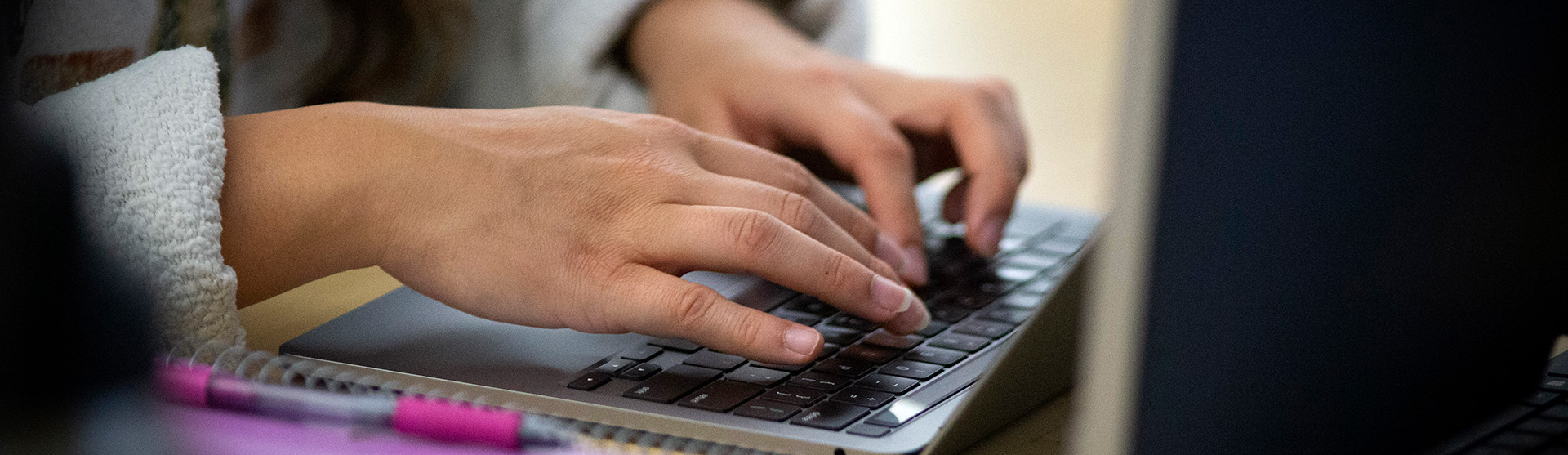 A pair of hands typing on a laptop computer keyboard.