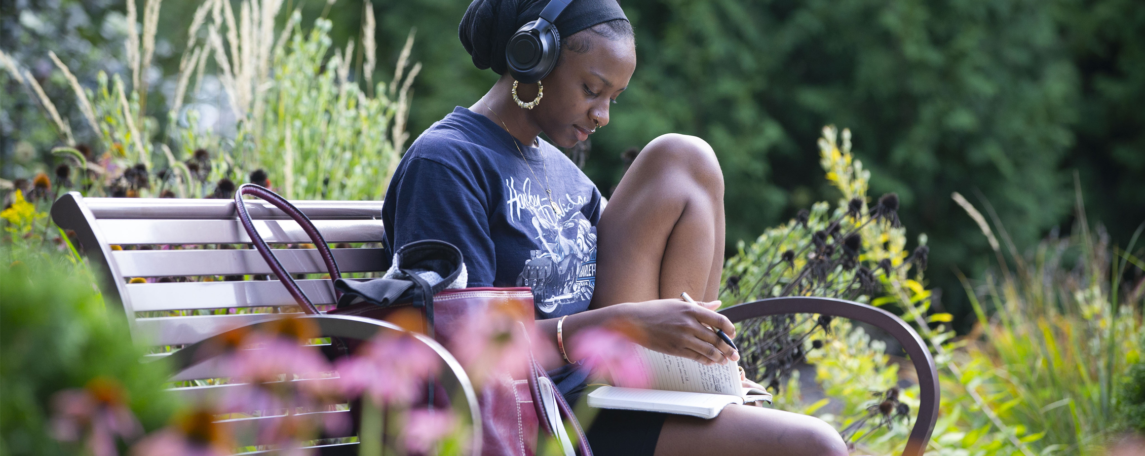 Student reading on bench in campus garden.