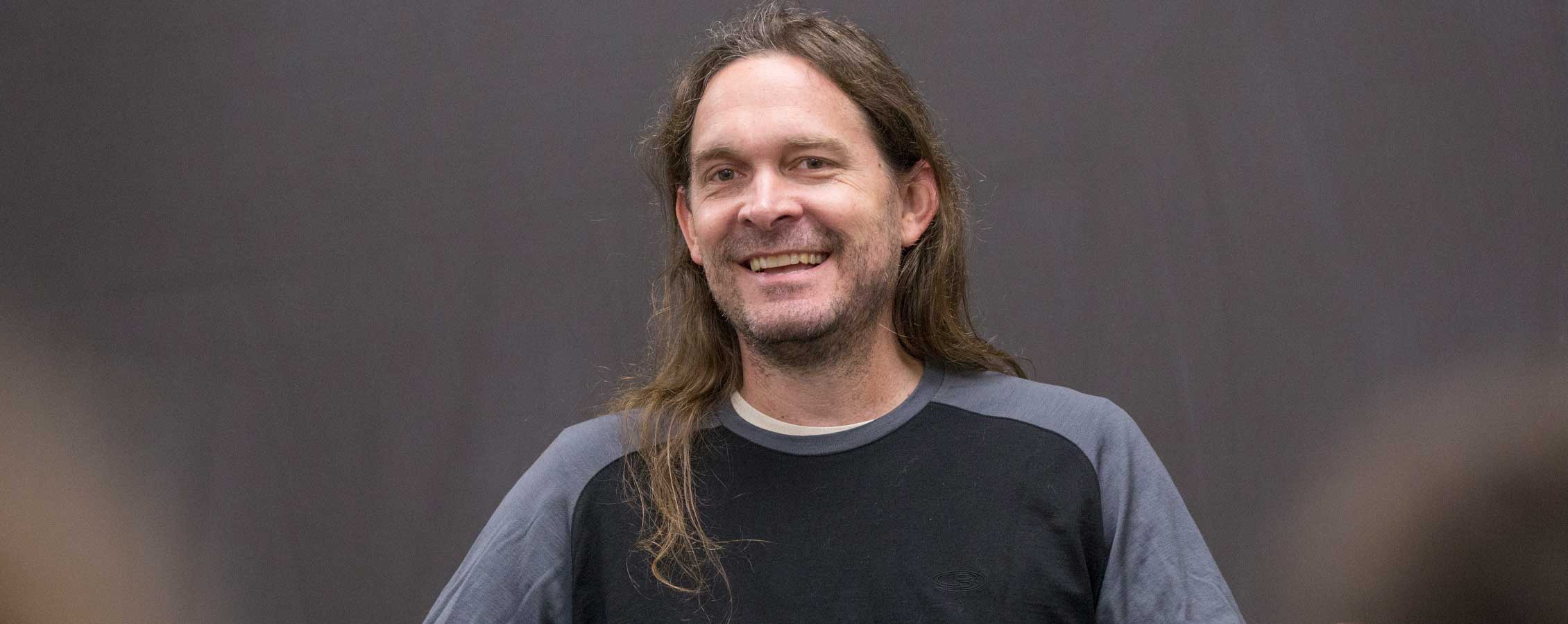 UW-Whitewater music professor Jeff Herriott smiles against a brown backdrop.