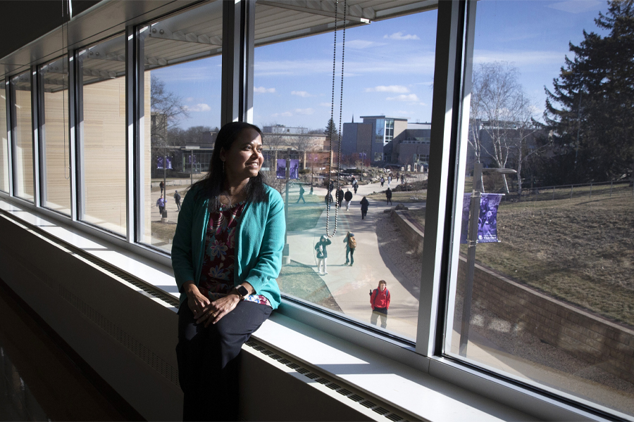 Rashiqa Kamal sits indoors on a windowsill and looks outside.