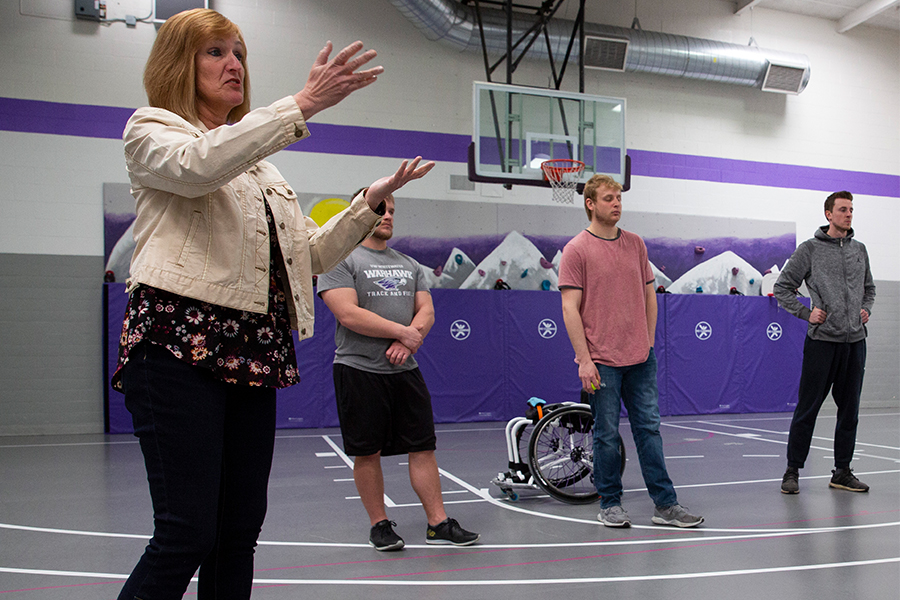 Kathleen Happel speaks with students in a gym.