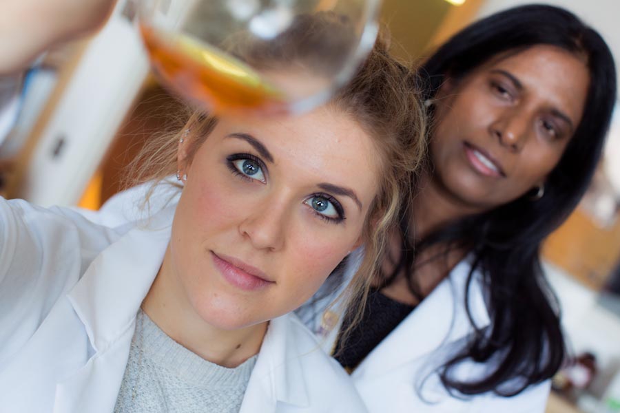 A students looks at liquid in a vial while her professor looks on.