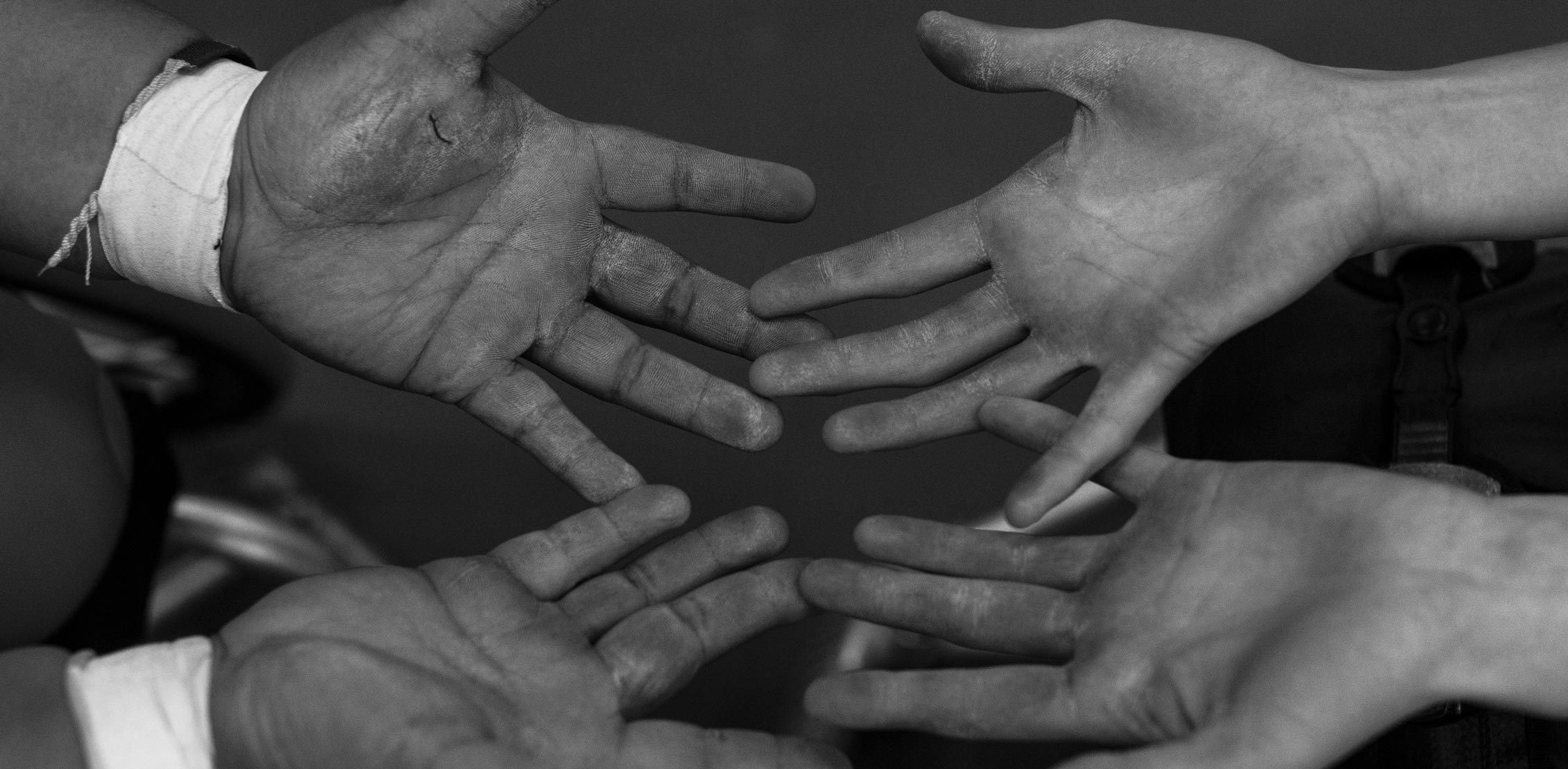 A black and white photo of four hands coming together.