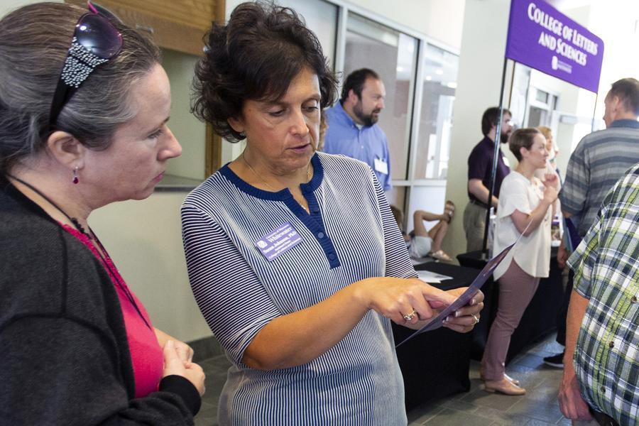 Two women speaking, one is showing the other something on a brochure