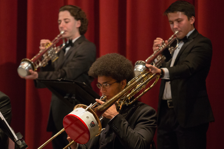 Alex Ostermann plays the trumpet while holding a mute into the horn.