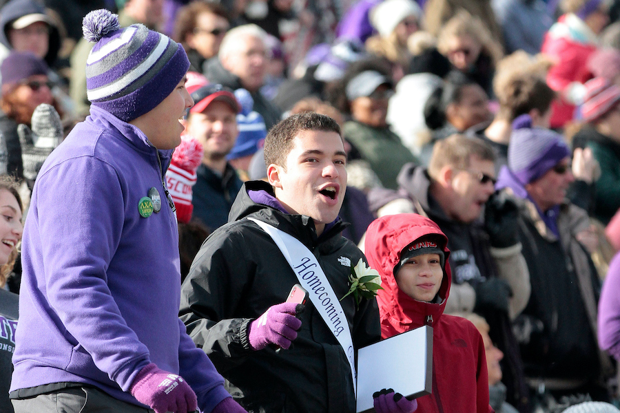 Brian Martinez cheers in the stands while wearing a Homecoming sash.