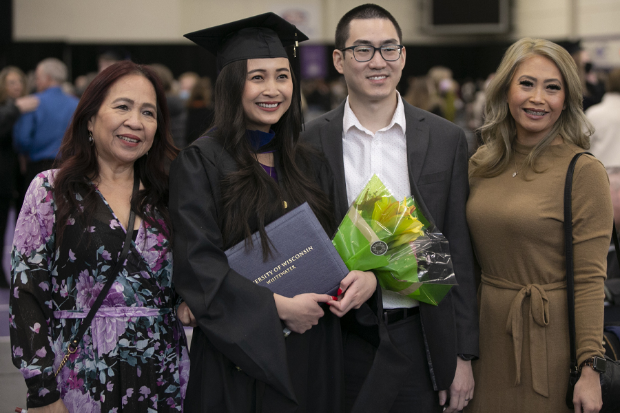 A graduate poses with her family at commencement.