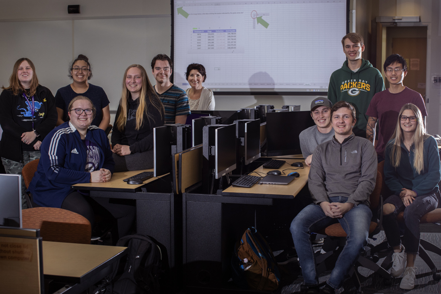 Students gathered in a classroom smile at the camera.