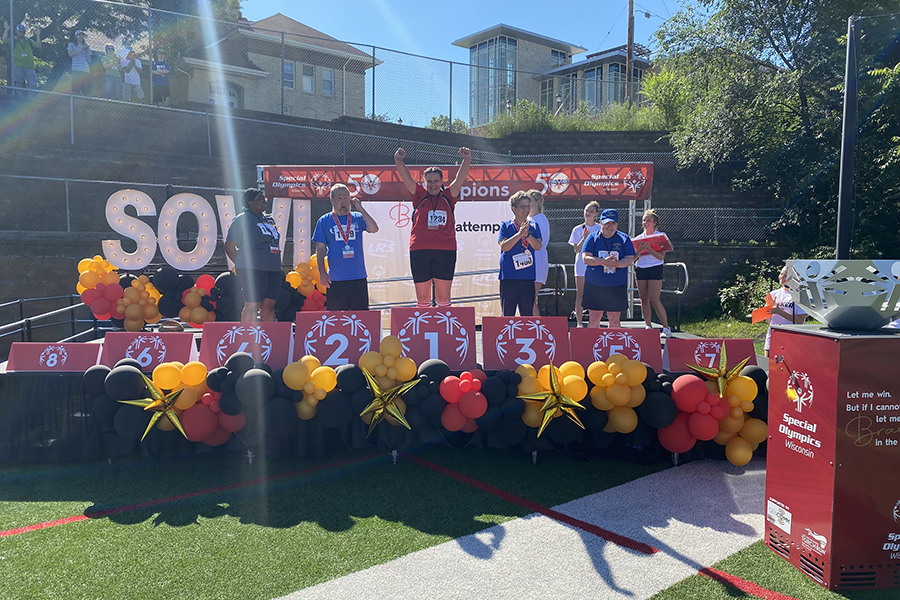 Special Olympics participants stand on a stage and celebrate.