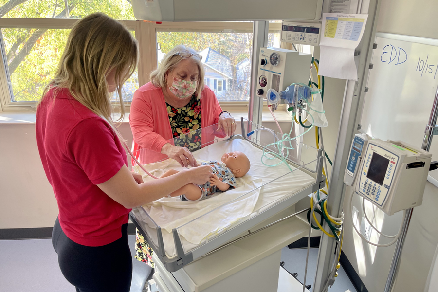 A nursing student works on a baby manikin.