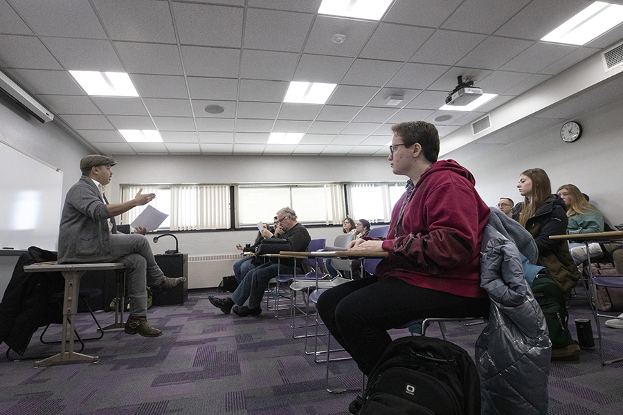 Nick Gulig sits on a table and speaks to a class.