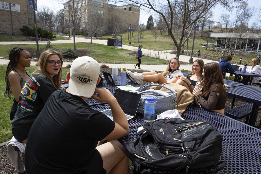 Students sit at a table outside the University Center.