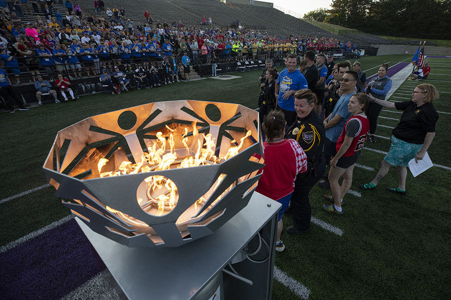 The Olympic flame burns surrounded by people in a stadium.