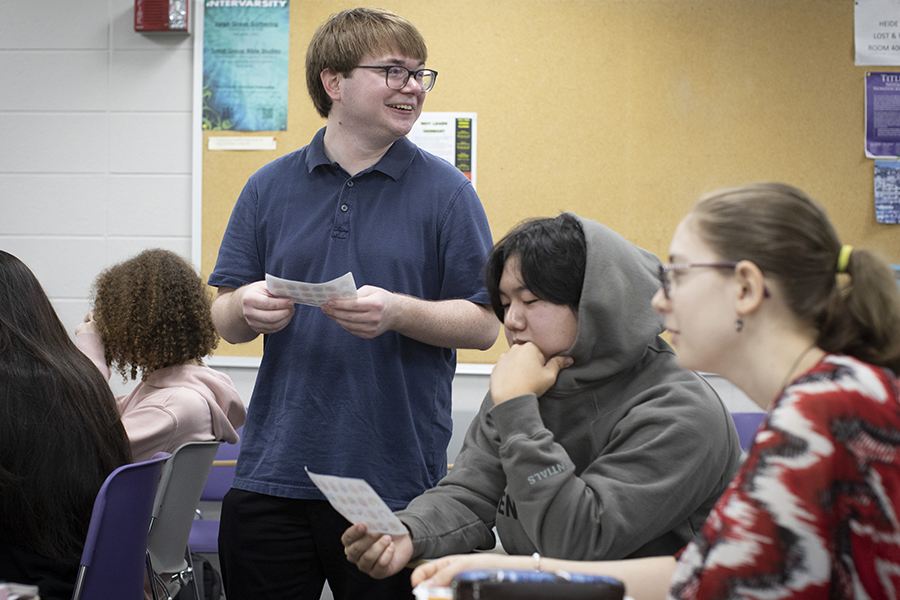 A student smiles as he stands in a classroom.