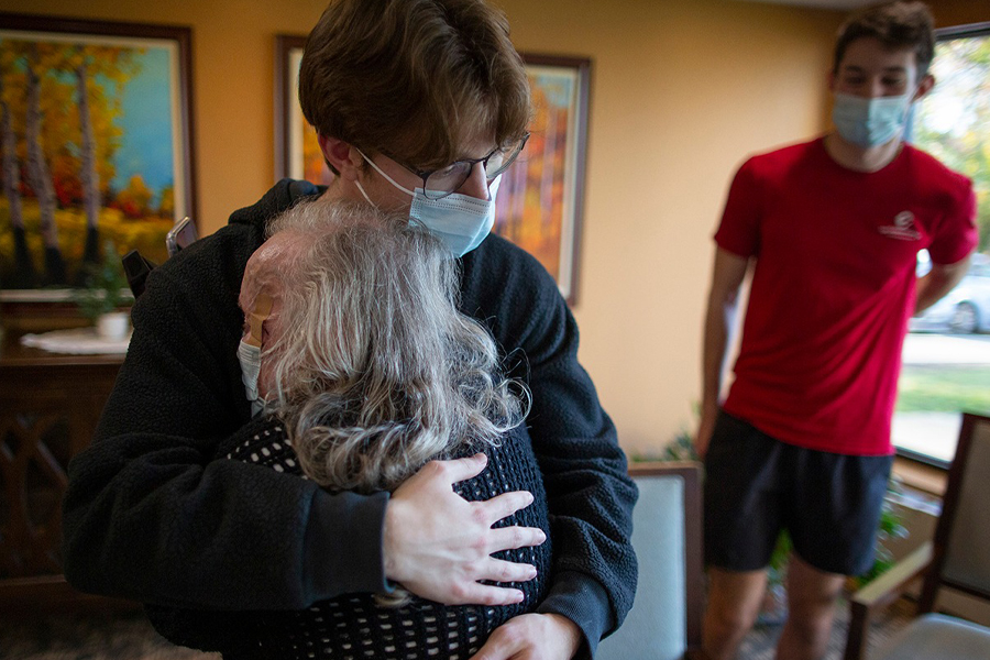 A student hugs an elderly woman.