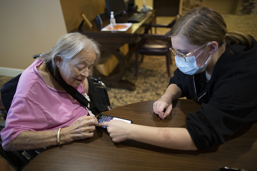 A student and a senior citizen look at a phone together.