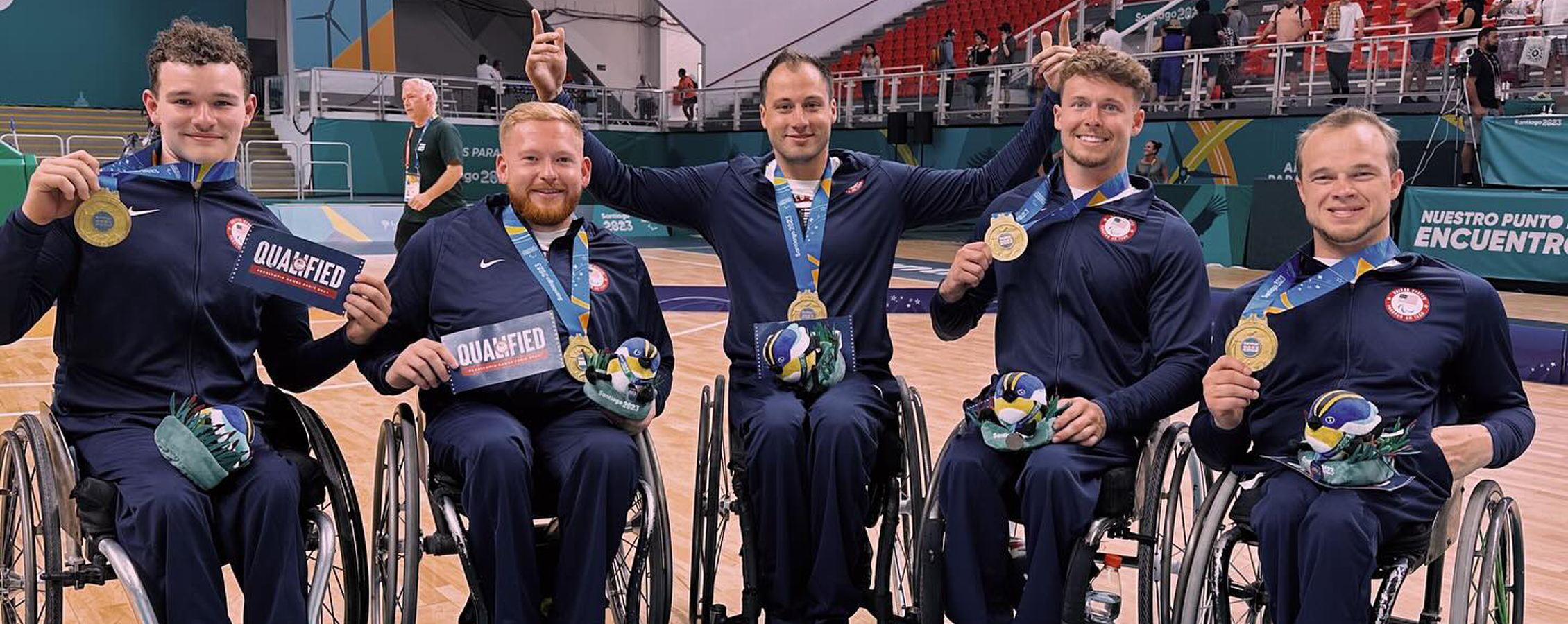 Five Warhawk wheelchair basketball athletes lined up showing their gold medals.