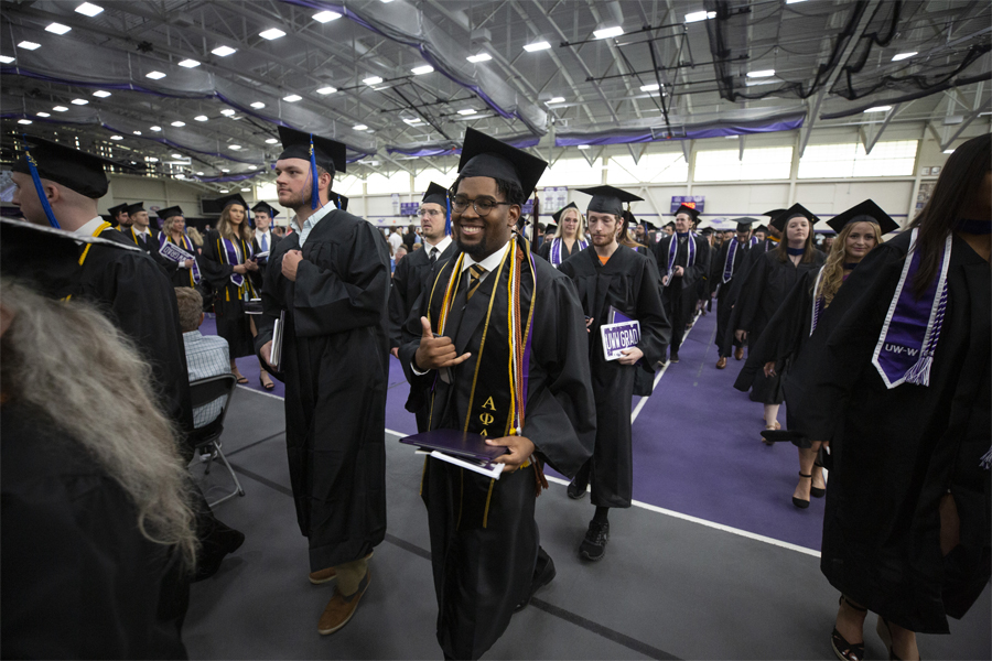 Students line up for graduation in their caps and gowns.