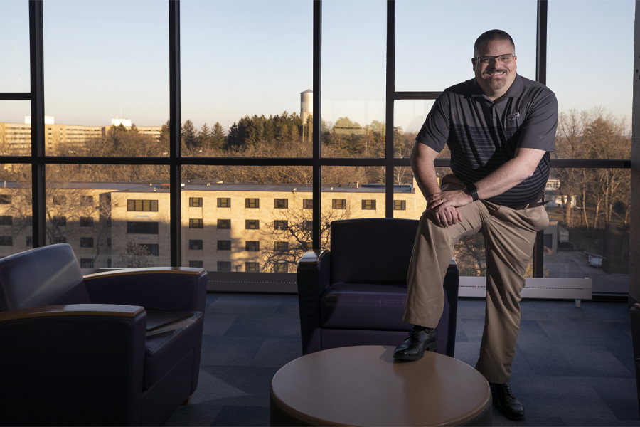 Terry Tumbarello stands in Ma'iingan Hall by a wall of windows.