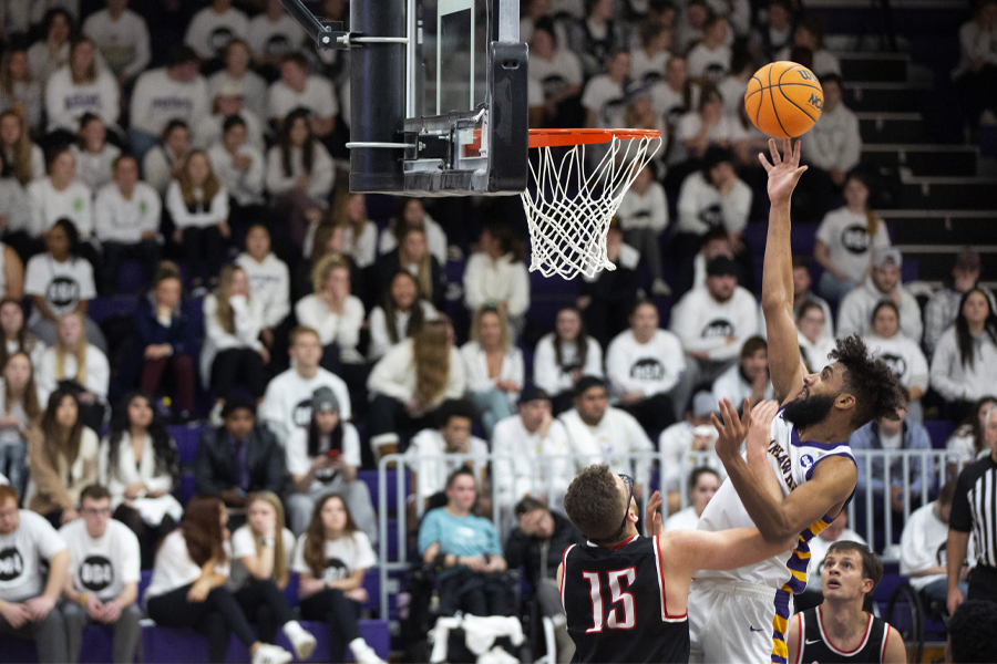 Tre Chislom jumps above a defender and shoots under the basket. 