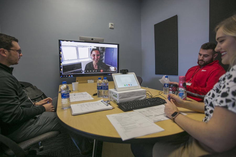 People sit at a table with a computer during a video conference.