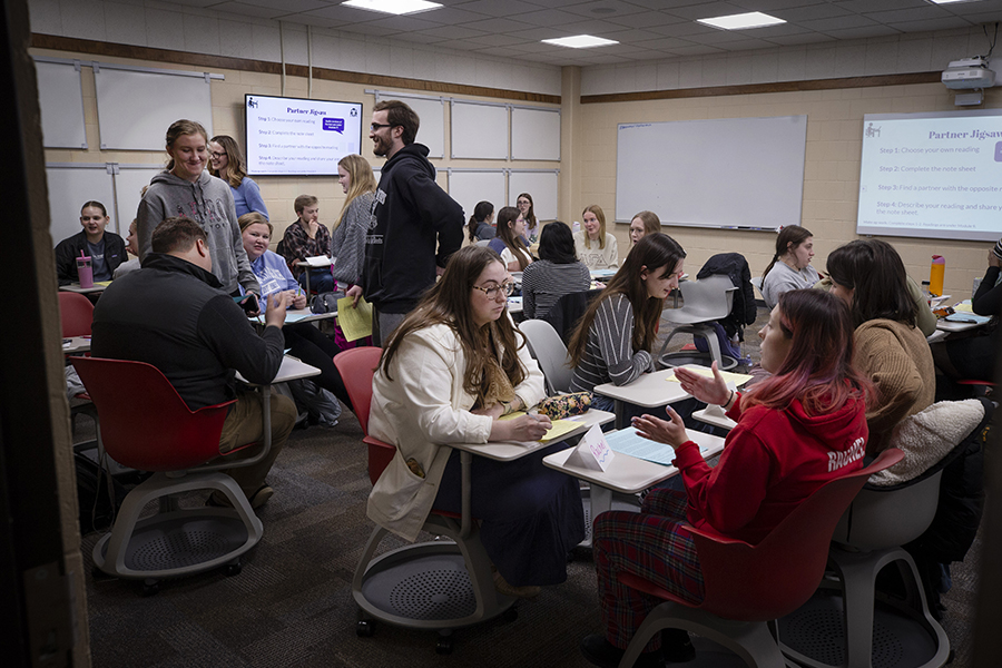 Students gather and chat in a classroom.