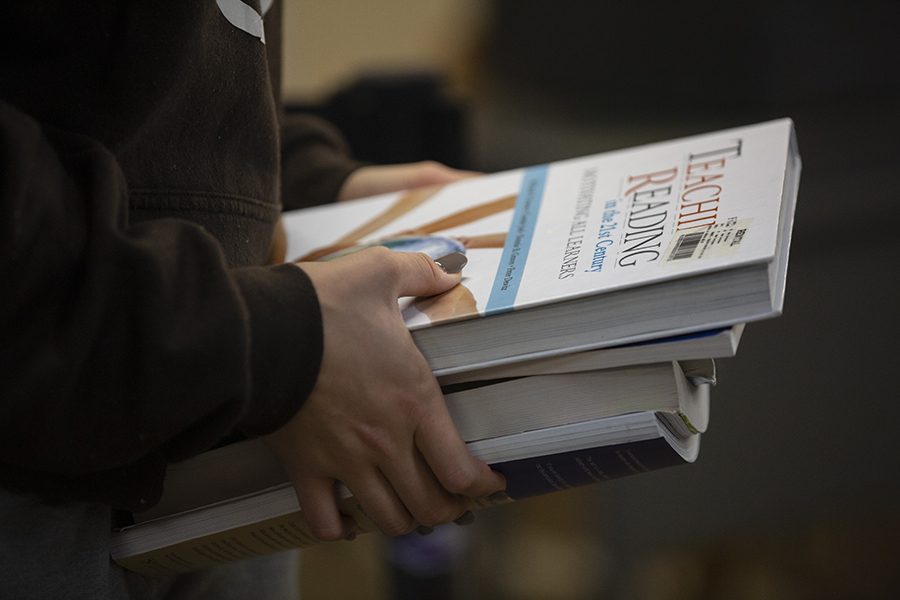 A close up photo of hands holding a stack of books.