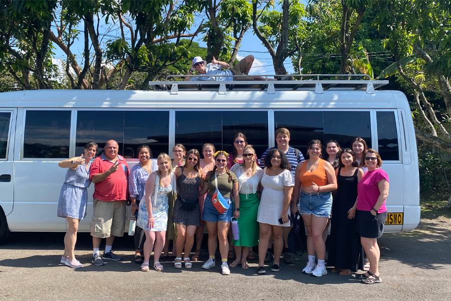 Students and faculty stand in front of a white van in Costa Rica.