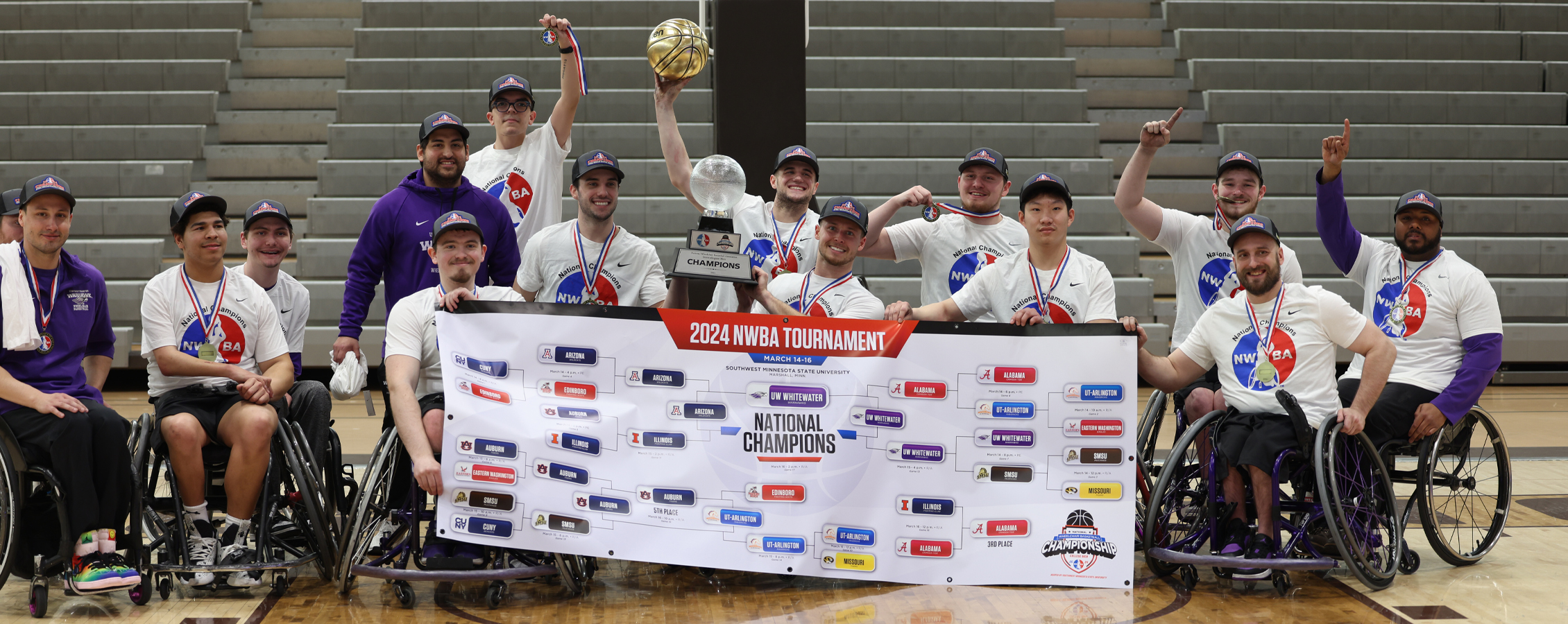 The wheelchair basketball team gathers together and holds a national champions banner.