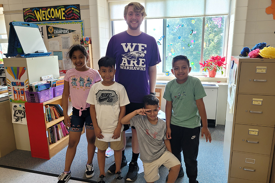 Kolden Severson stands with children in a classroom.