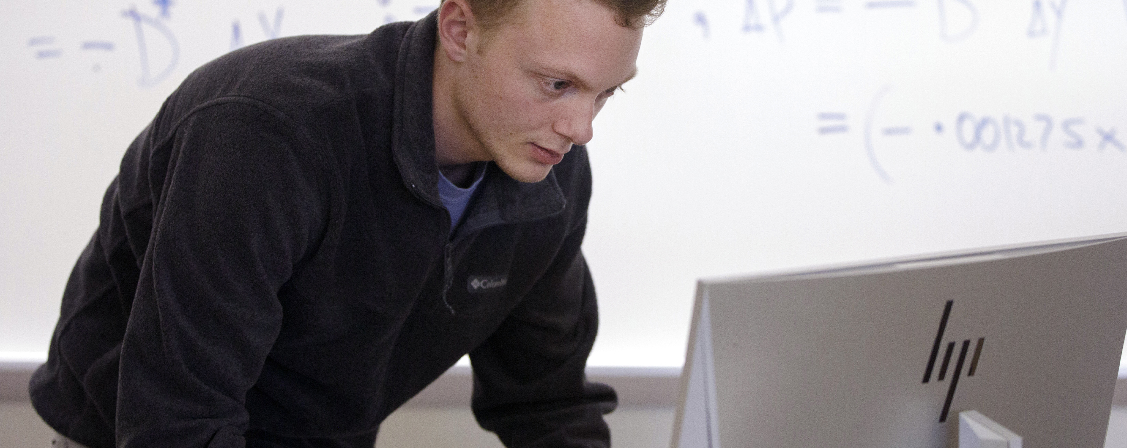 Dylan Riley bends down to look at a computer.